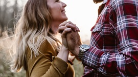 Ein Foto eines Mannes und einer Frau, die sich glücklich ansehen, während sie Hände halten