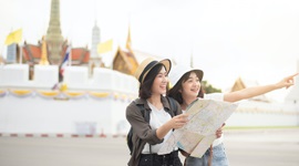 Ein Foto von zwei asiatischen Frauen, die eine Karte halten, während eine in die Ferne zeigt